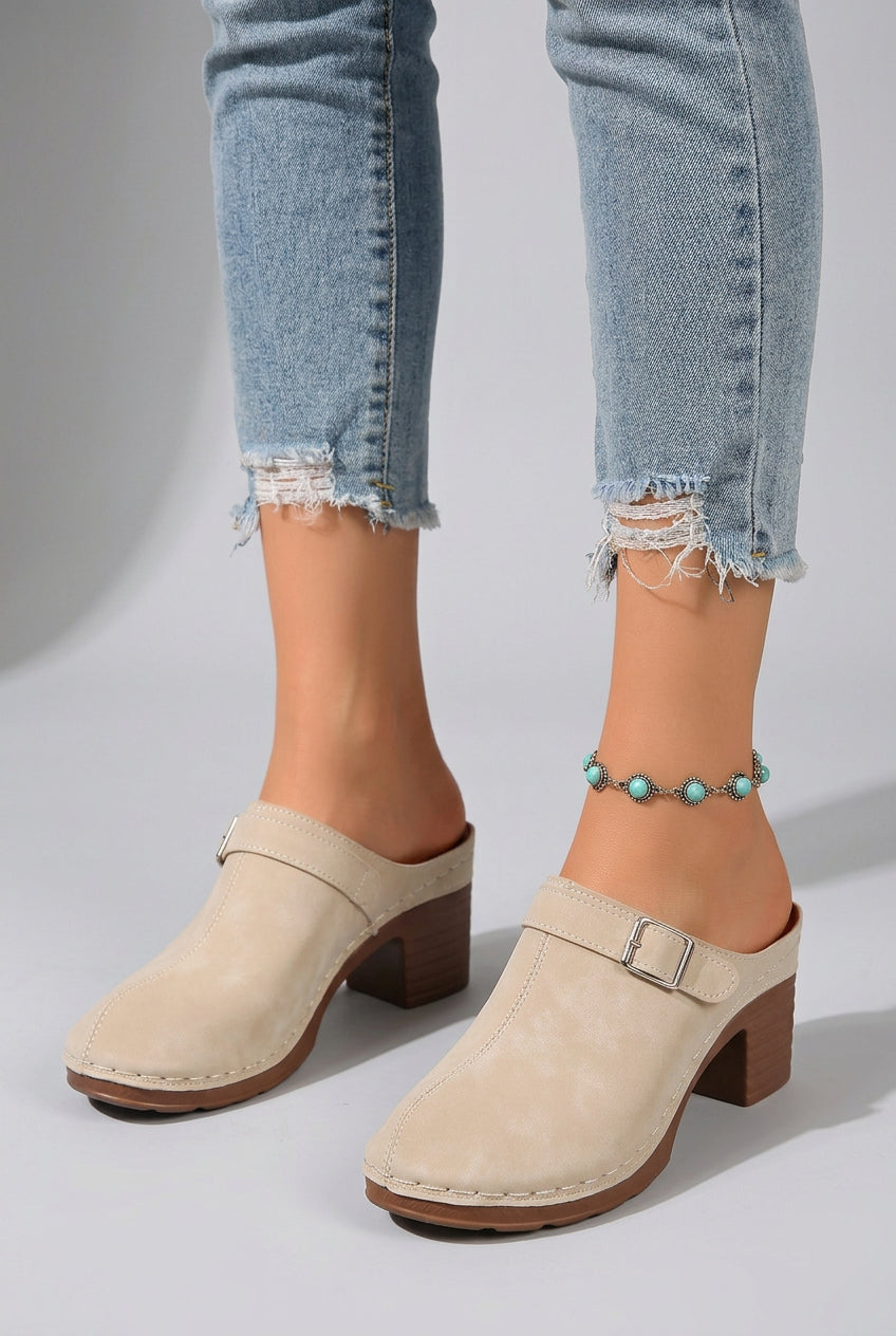 Beige clogs with brown soles worn on a beach setting