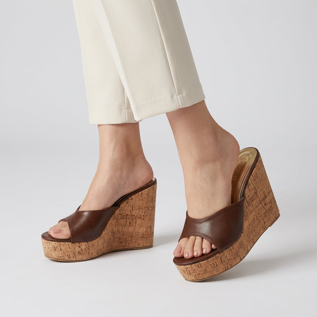Brown wedge sandals with cork sole on a dark surface